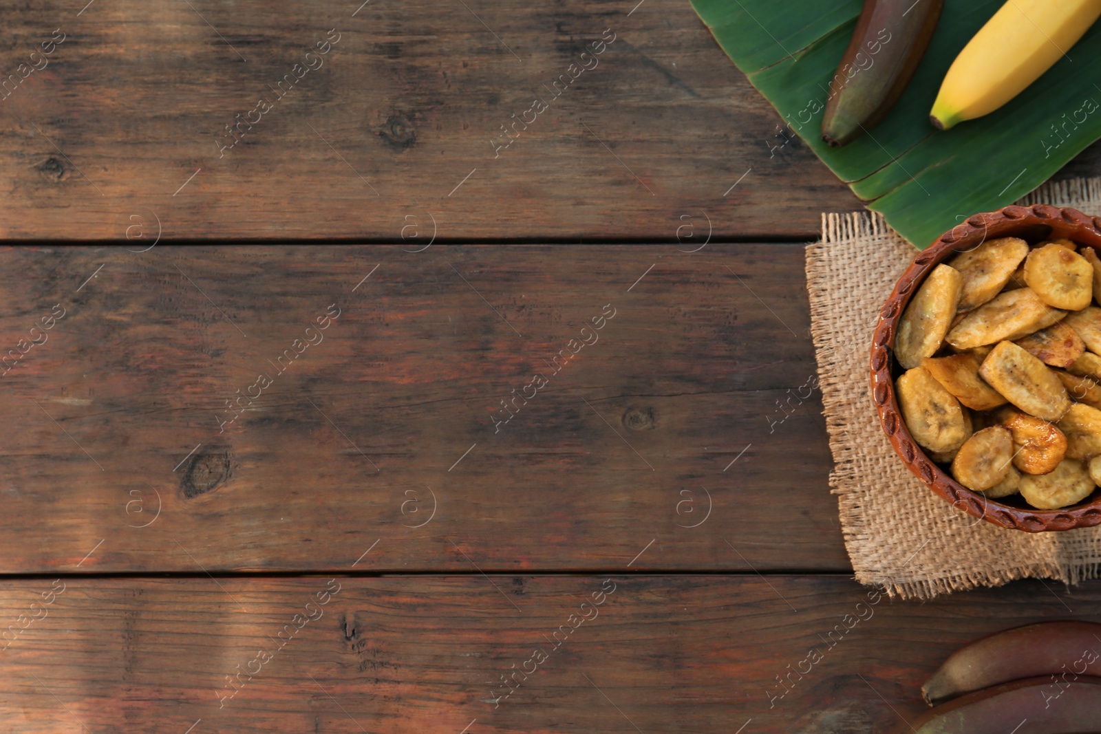 Photo of Tasty deep fried banana slices and fresh fruits on wooden table, flat lay. Space for text