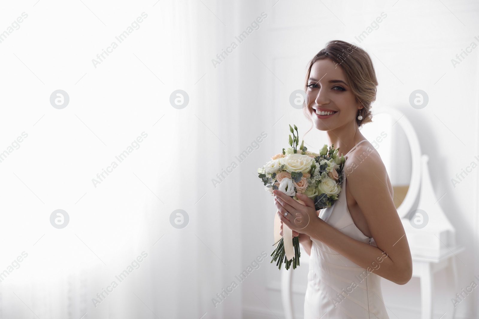 Photo of Bride in beautiful wedding dress with bouquet indoors. Space for text