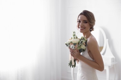Photo of Bride in beautiful wedding dress with bouquet indoors. Space for text