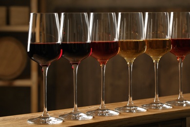 Photo of Glasses of different wines in cellar. Expensive collection