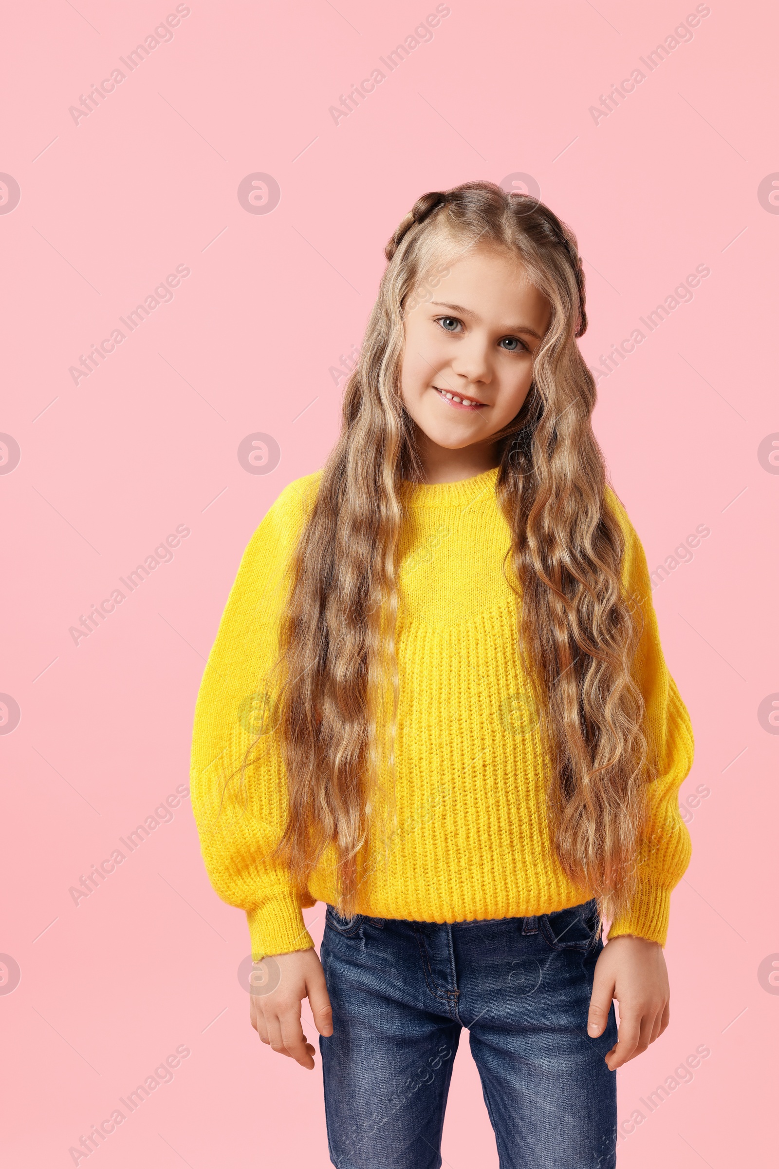 Photo of Cute little girl with braided hair on pink background