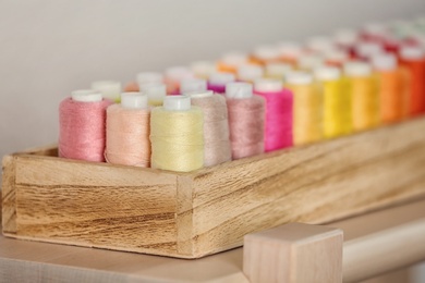 Photo of Wooden box with color sewing threads, closeup