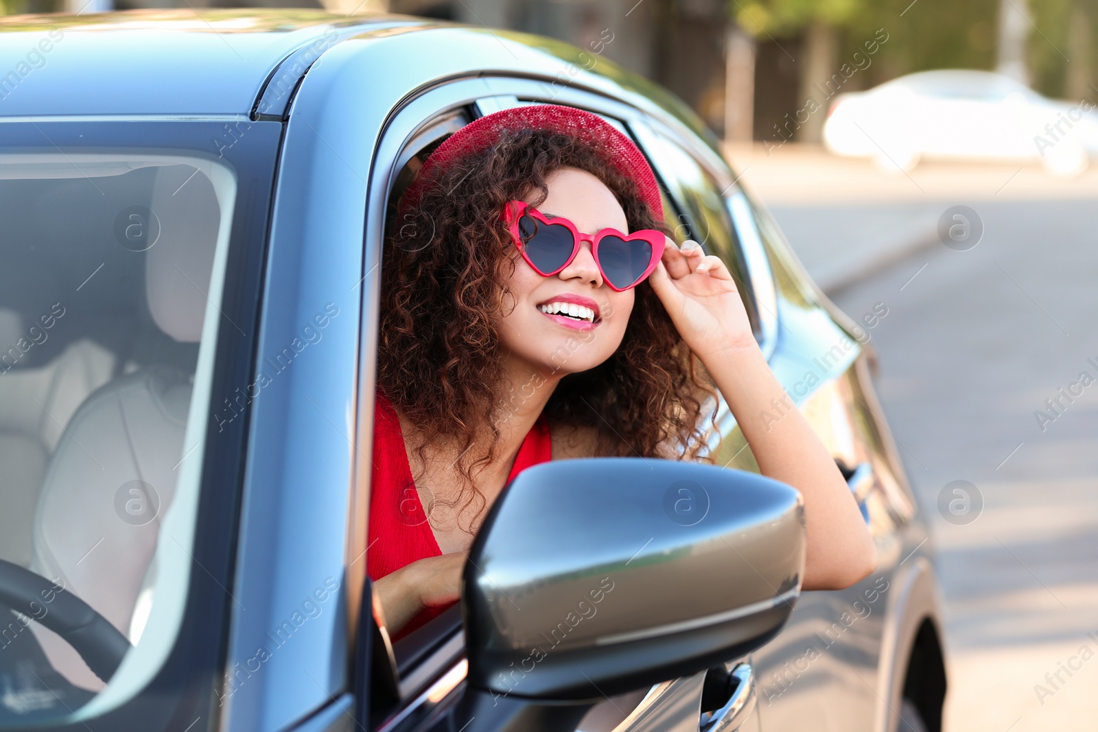 Photo of Young beautiful African-American woman wearing heart shaped glasses in car