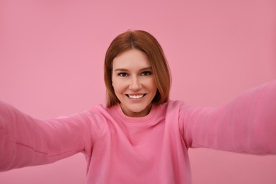 Photo of Beautiful woman taking selfie on pink background