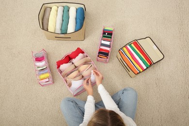 Woman folding clothes on floor, top view. Japanese storage system