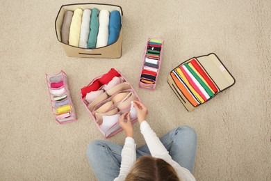 Photo of Woman folding clothes on floor, top view. Japanese storage system