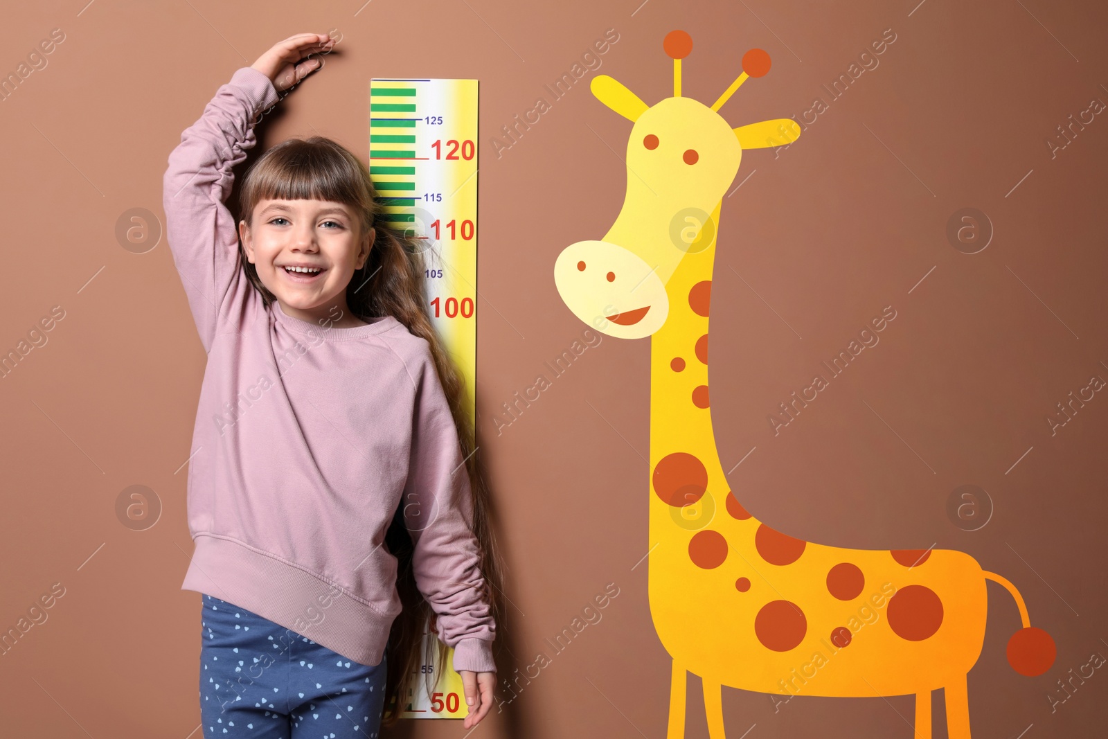 Image of Little girl measuring height and drawing of giraffe on brown background