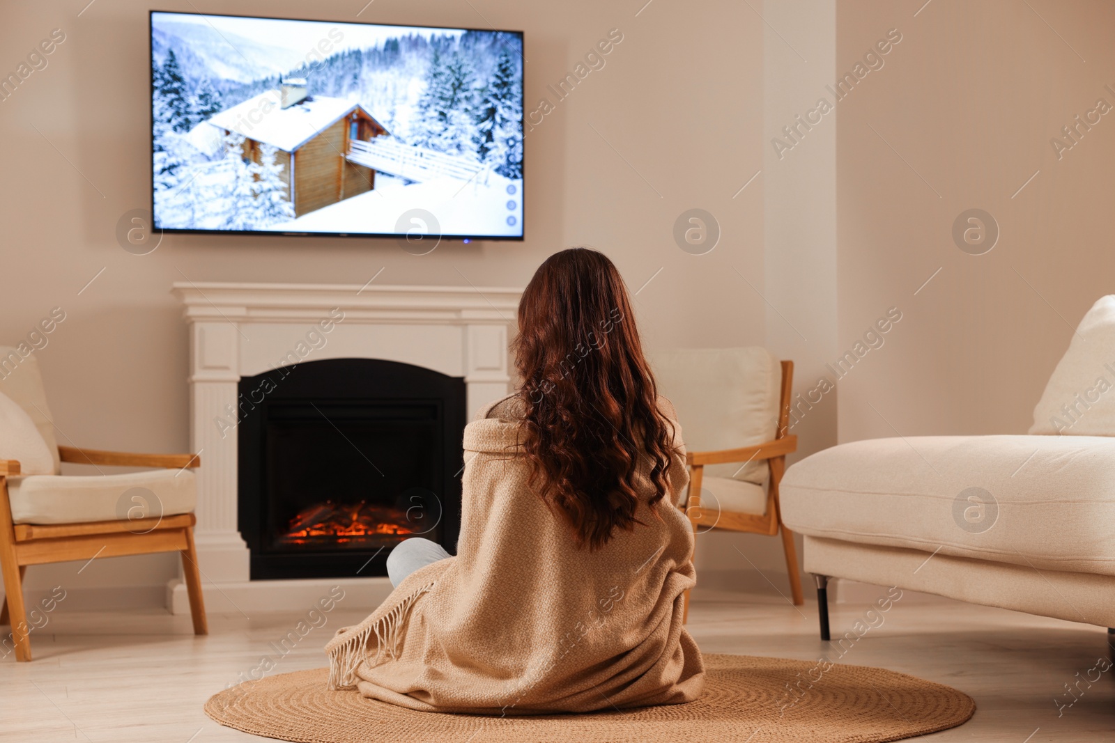 Photo of Young woman relaxing on floor near fireplace at home, back view