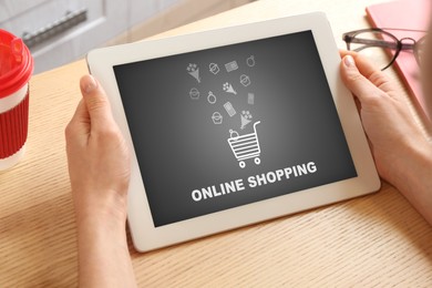 Image of Woman using tablet for online shopping at wooden table, closeup