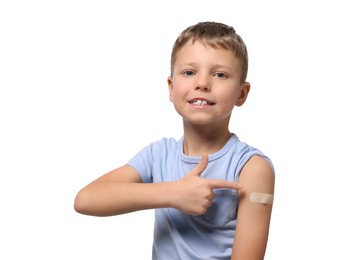Boy pointing at sticking plaster after vaccination on his arm against white background