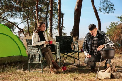 Couple resting near bonfire at camping site
