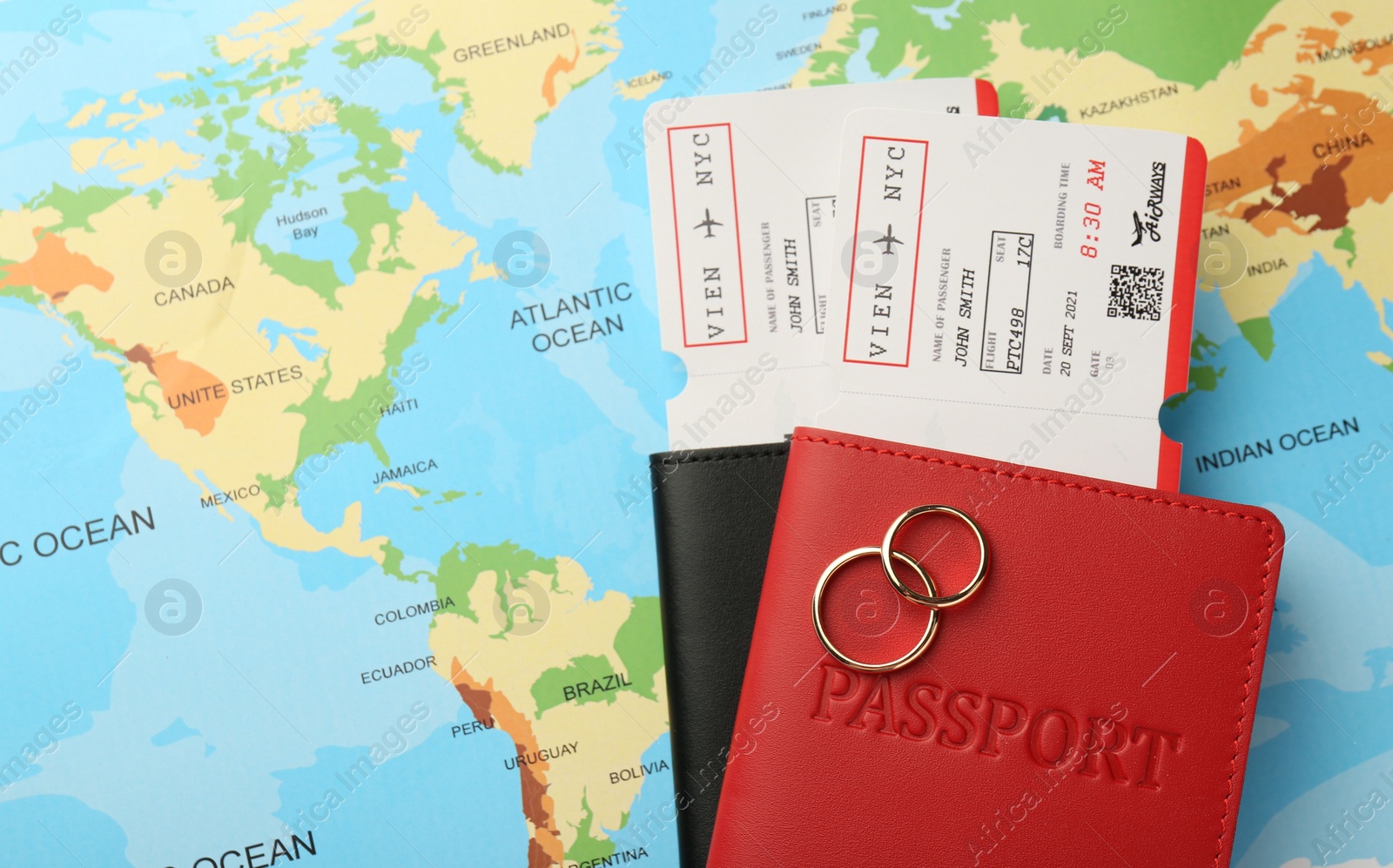 Photo of Honeymoon concept. Plane tickets, passports and golden rings on world map, top view