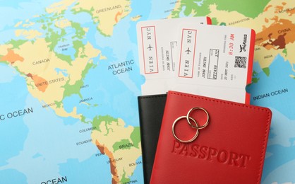 Honeymoon concept. Plane tickets, passports and golden rings on world map, top view