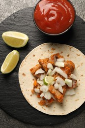 Photo of Delicious taco with vegetables, meat and ketchup on grey textured table, top view