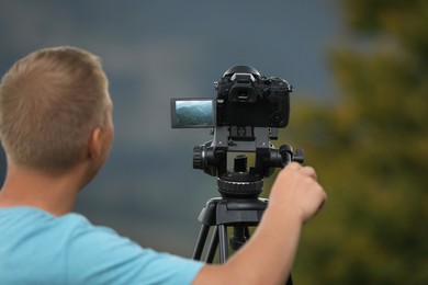 Photo of Photographer taking video with modern camera on tripod in nature