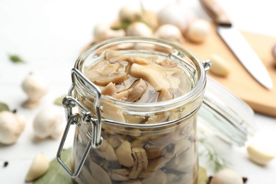 Photo of Glass jar of tasty pickled mushrooms, closeup