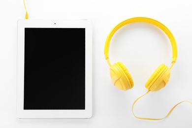 Photo of Tablet with blank screen and headphones on white background, top view