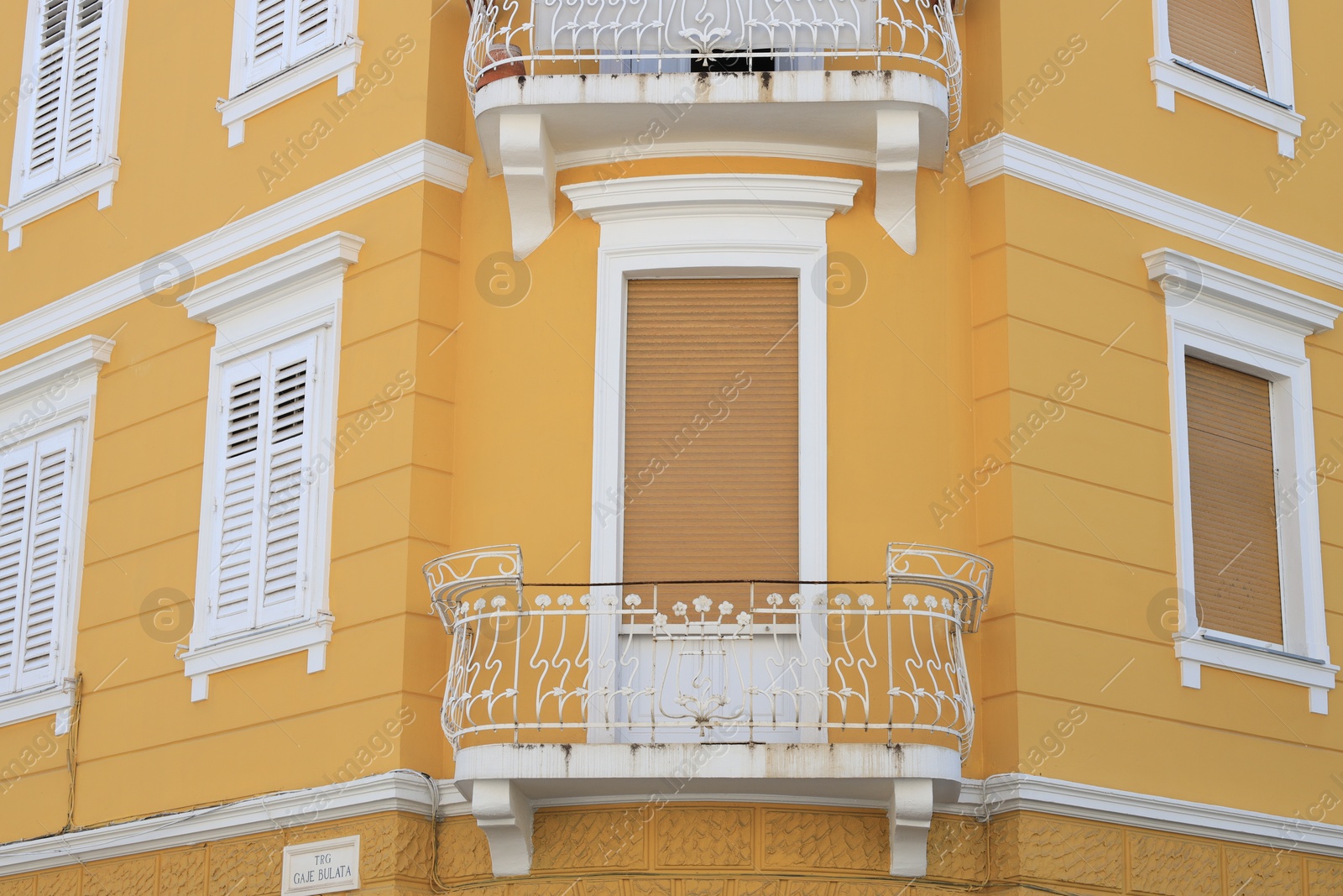 Photo of View of beautiful yellow building with balconies outdoors