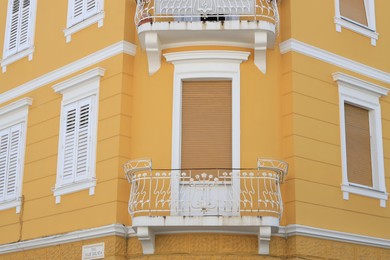 Photo of View of beautiful yellow building with balconies outdoors