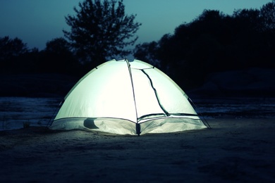 Small camping tent glowing in twilight outdoors