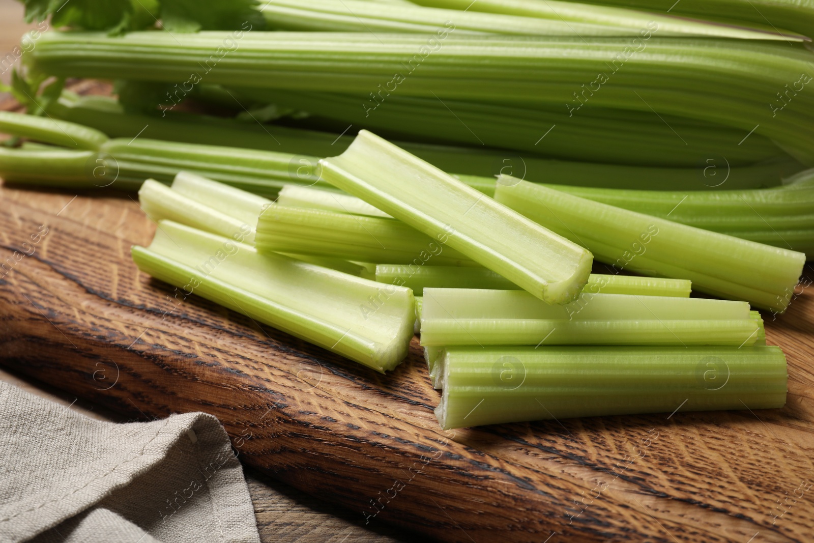 Photo of Fresh cut celery on wooden board, closeup