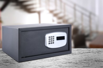 Image of Closed steel safe with electronic lock on light grey table indoors