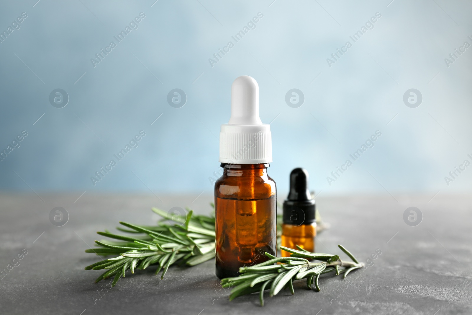 Photo of Bottles with rosemary essential oil on table