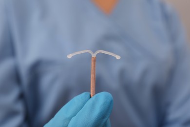 Photo of Doctor holding T-shaped intrauterine birth control device, closeup