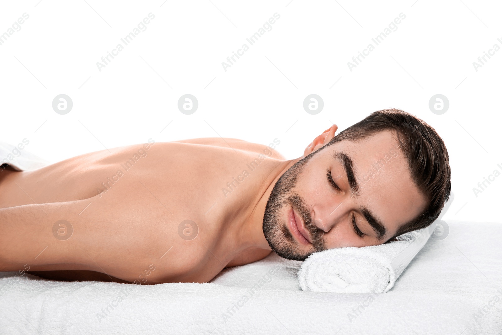 Photo of Handsome man relaxing on massage table against white background. Spa service