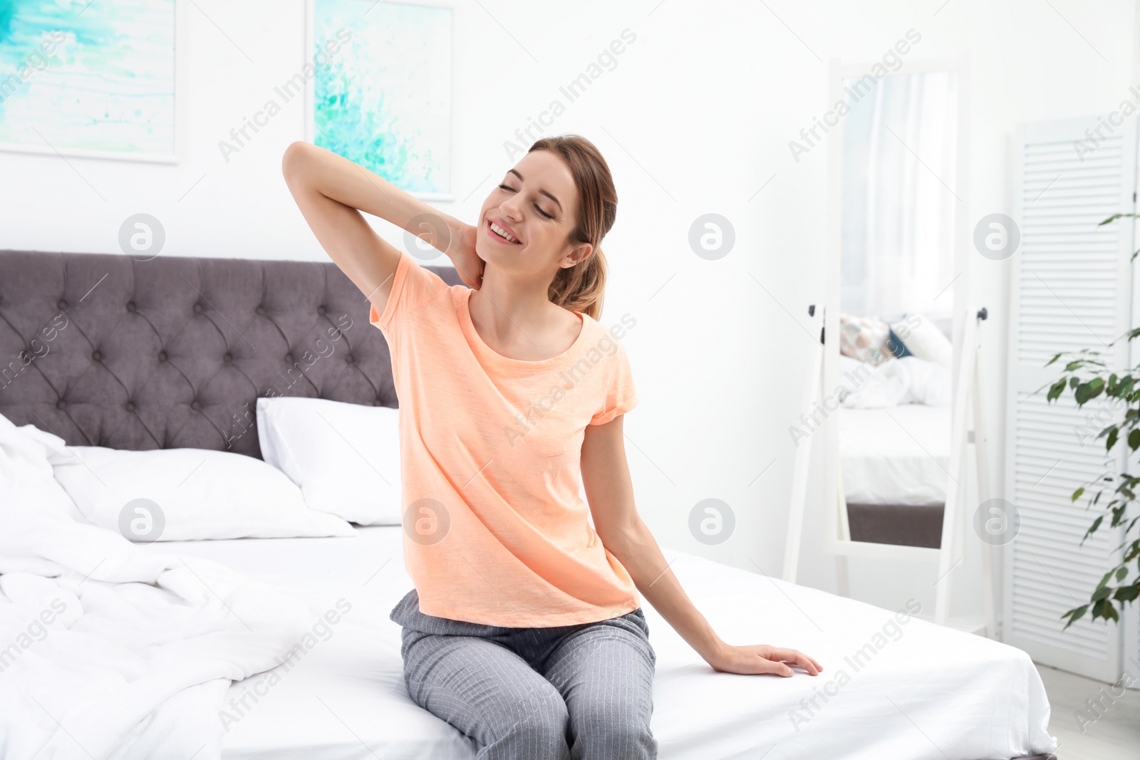 Photo of Young beautiful woman stretching on bed at home. Morning fitness