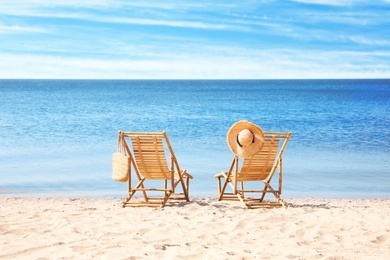 Photo of Wooden deck chairs on sandy beach near sea