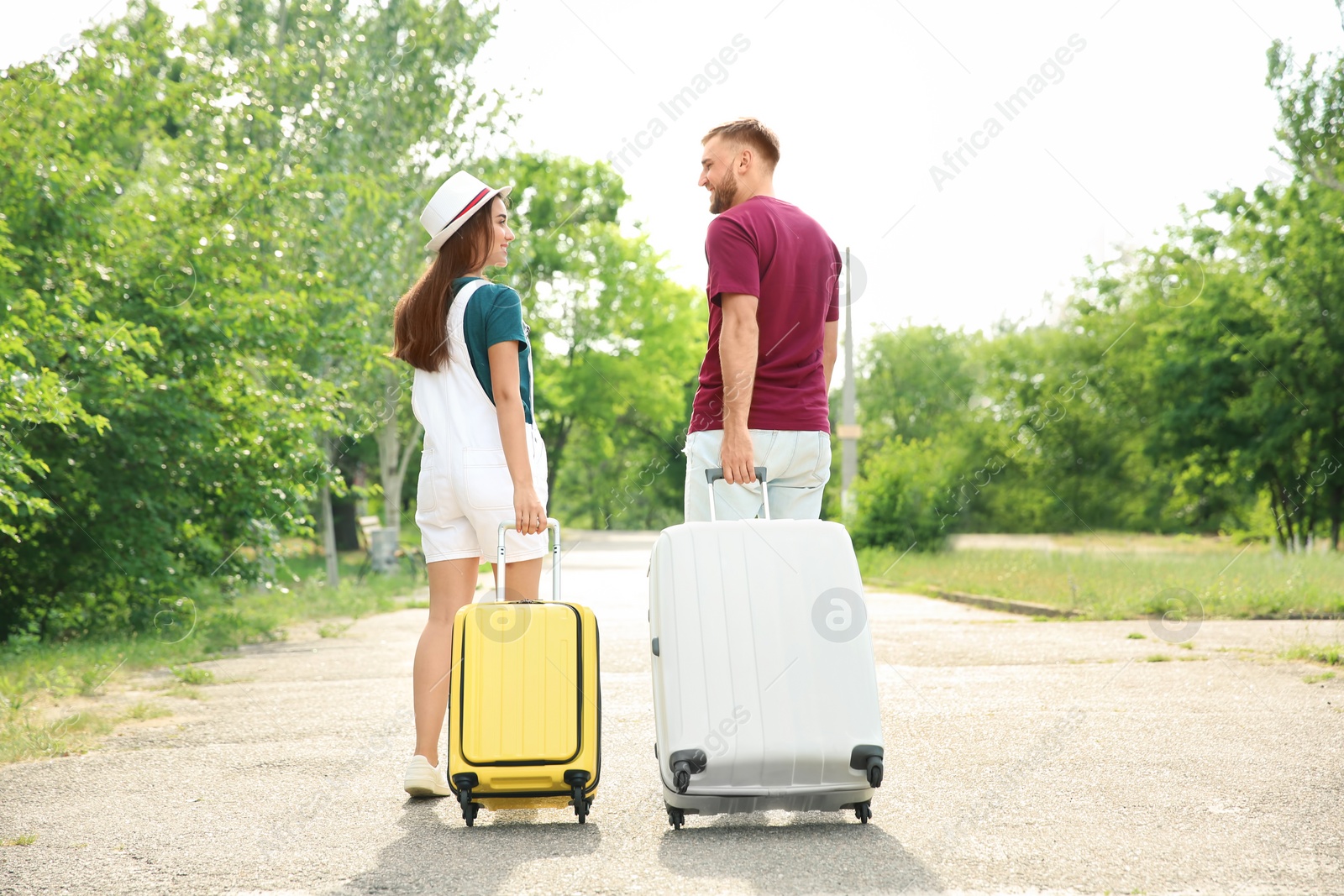 Photo of Beautiful young couple with suitcases packed for summer journey walking outdoors
