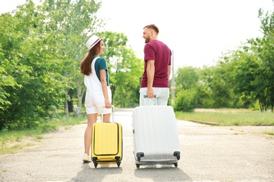 Beautiful young couple with suitcases packed for summer journey walking outdoors