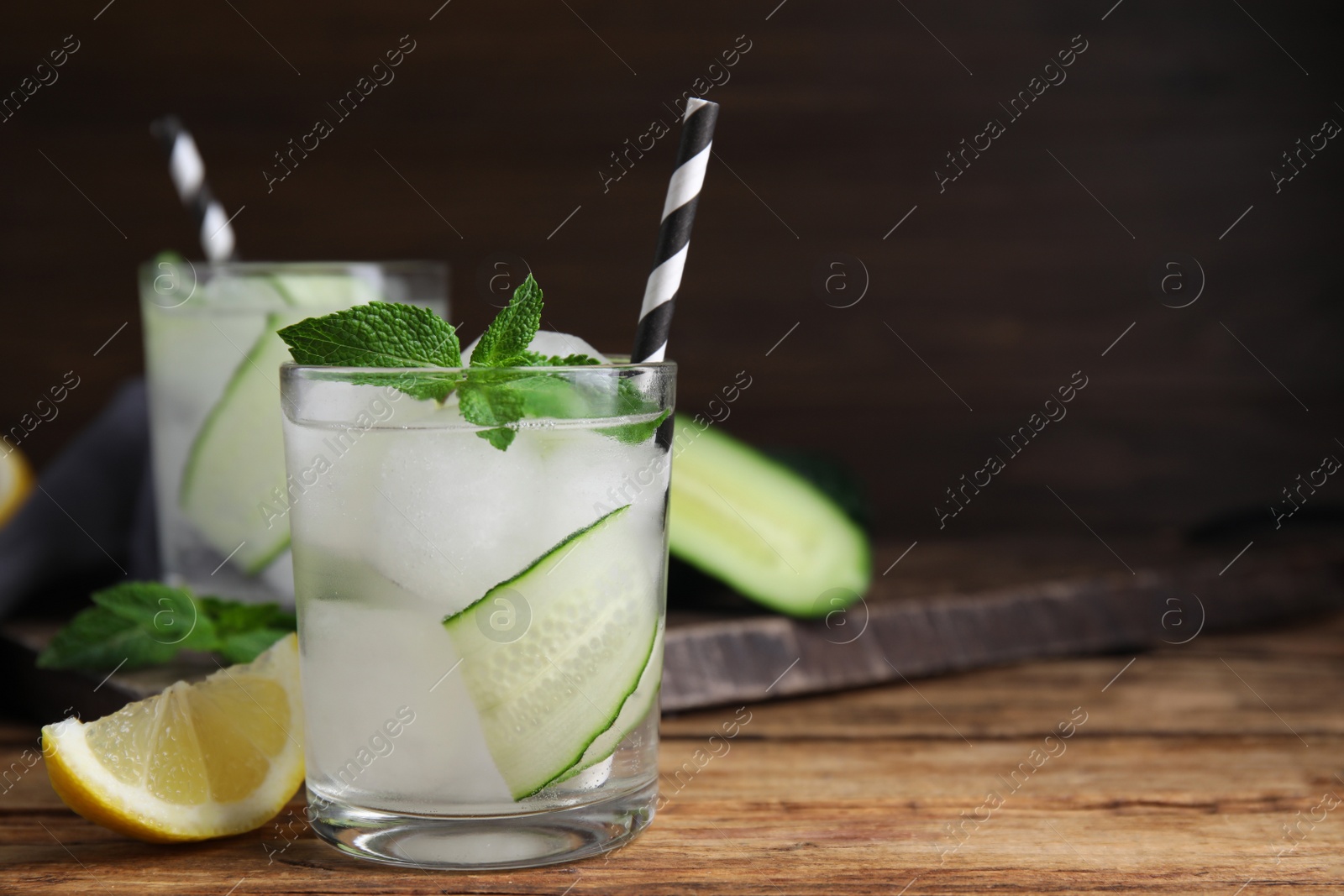 Photo of Glasses of refreshing cucumber water with mint on wooden table, space for text