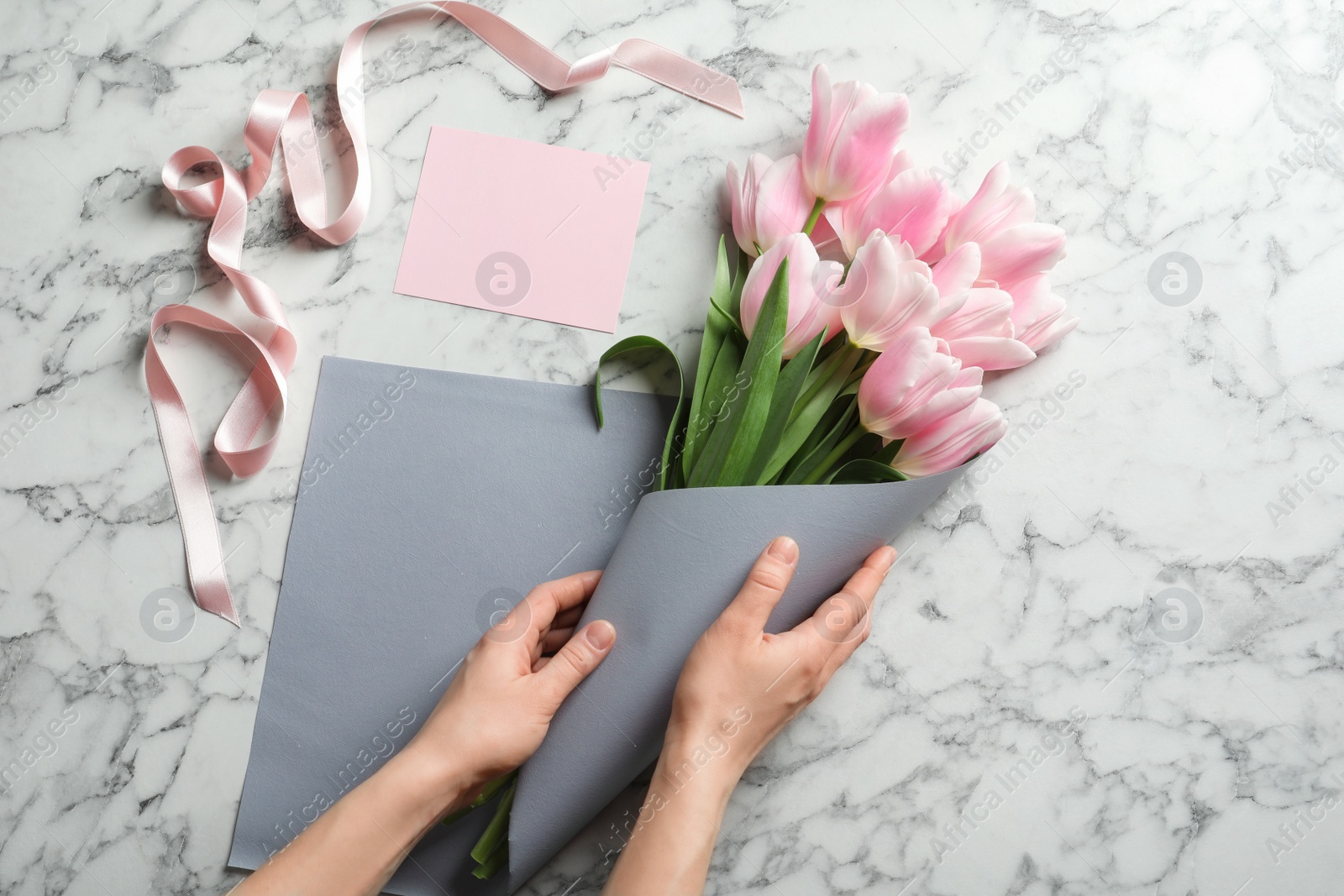 Photo of Female florist creating beautiful tulip bouquet for Mother's Day at table