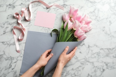 Female florist creating beautiful tulip bouquet for Mother's Day at table