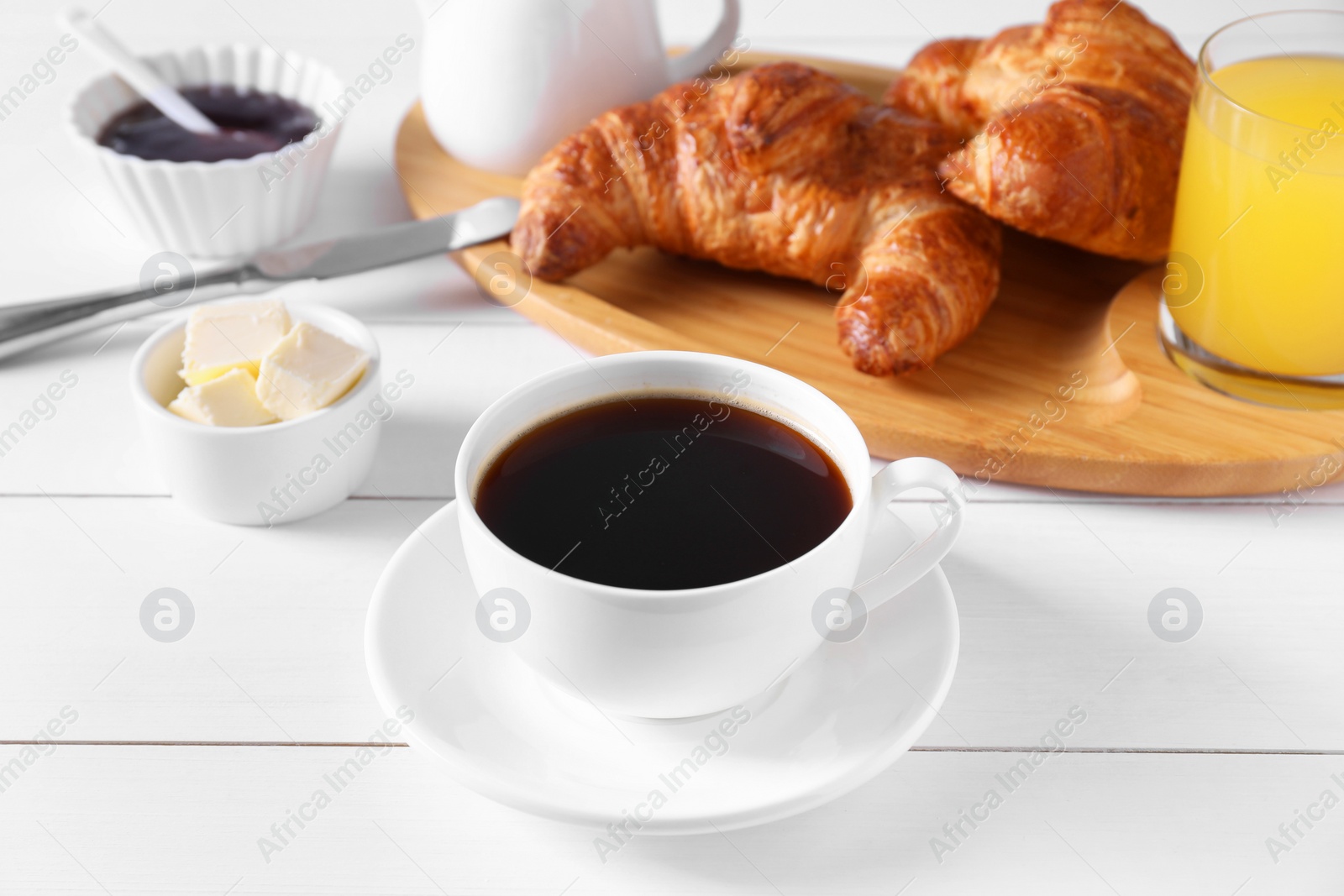 Photo of Fresh croissants, butter and coffee on white wooden table. Tasty breakfast