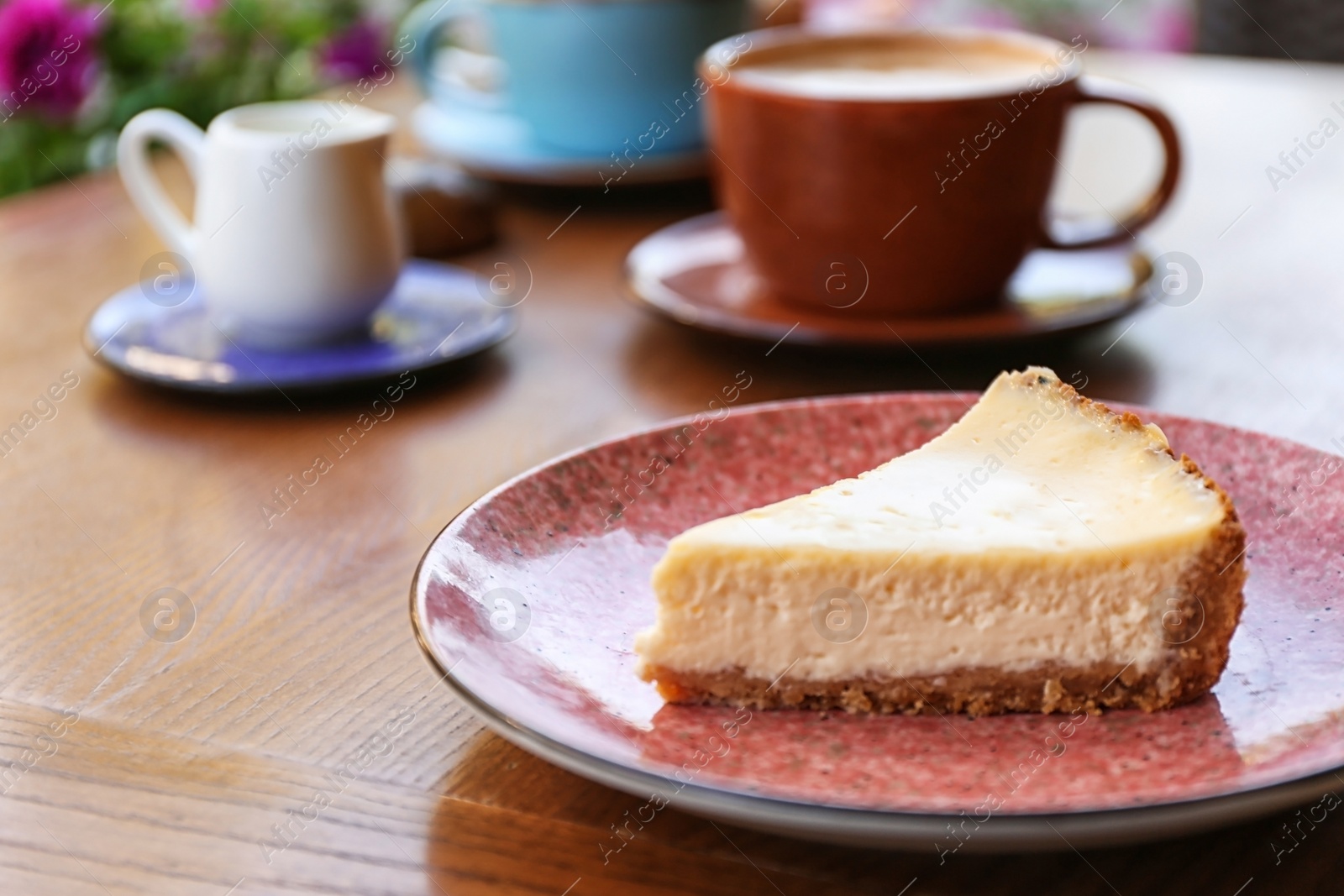 Photo of Plate with slice of cheesecake on wooden table