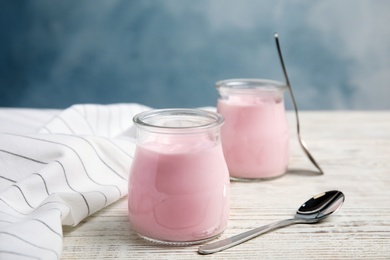 Glass jars with creamy yogurt served on white wooden table