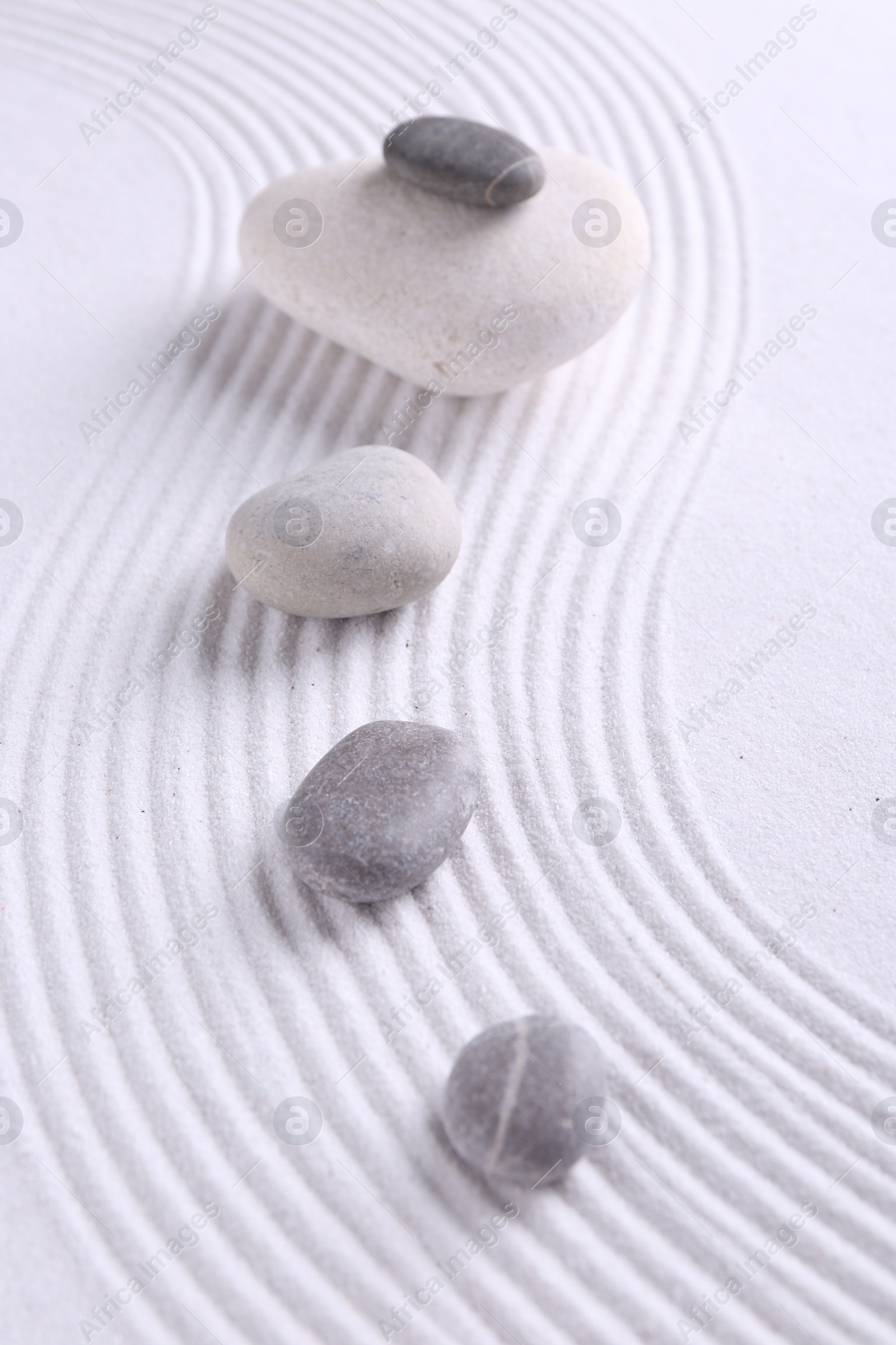 Photo of Zen garden stones on white sand with pattern