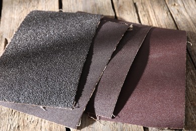 Photo of Many coarse sandpapers on wooden table, closeup