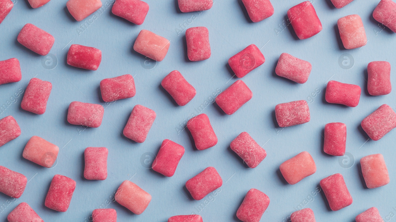 Photo of Many sweet chewing gums on light blue background, flat lay