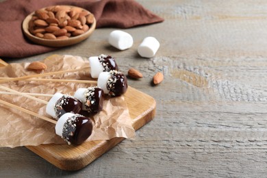 Photo of Delicious marshmallows covered with chocolate on wooden table. Space for text