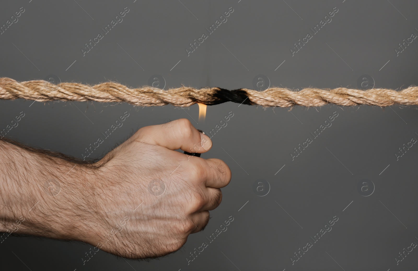 Photo of Man scorching frayed rope on dark background