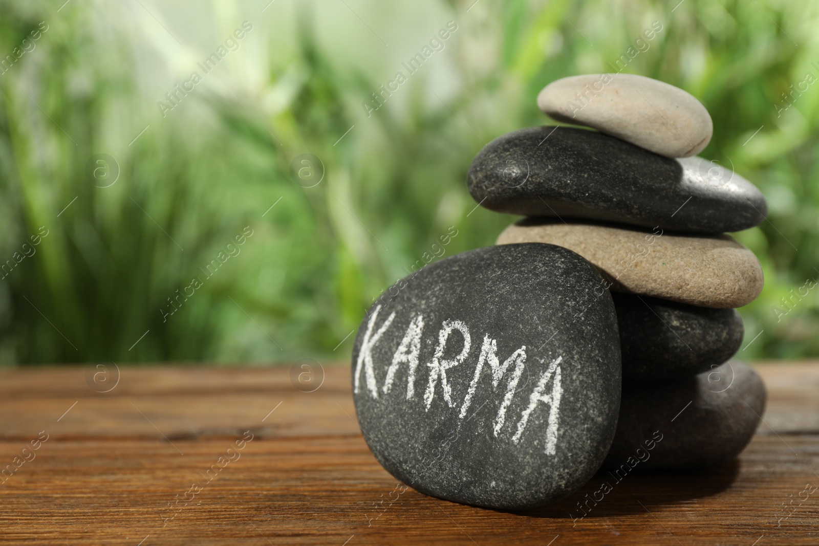 Photo of Stones with word Karma on wooden table, closeup. Space for text