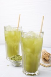 Photo of Delicious iced green matcha tea and powder on white table