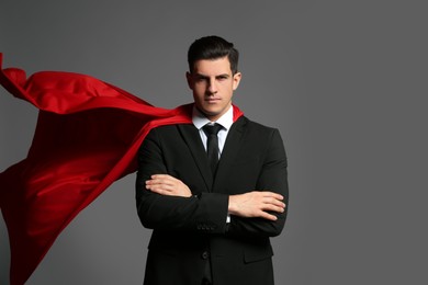 Photo of Businessman wearing superhero cape on grey background