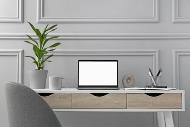 Photo of Stylish workspace with laptop, stationery and houseplant on wooden desk