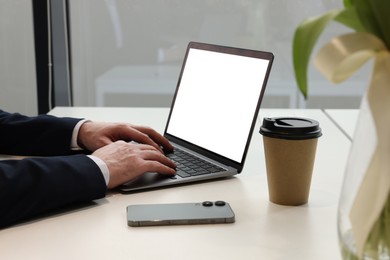 Photo of Man working on laptop at white desk in office, closeup
