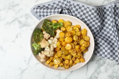 Baked yellow carrot with broccoli and cauliflowers on white marble table, top view